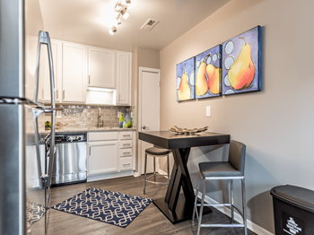 A kitchen with a table and chairs and a painting of pears on the wall.